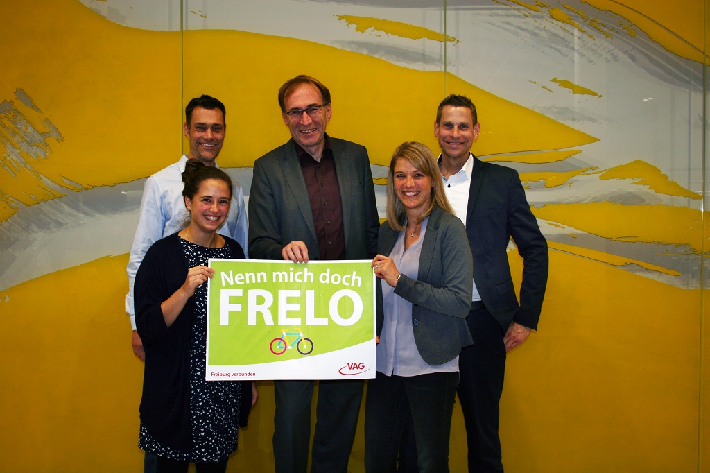 Personengruppe hält Schild mit Namen "Frelo" für das kommende Fahrradverleihsystem
